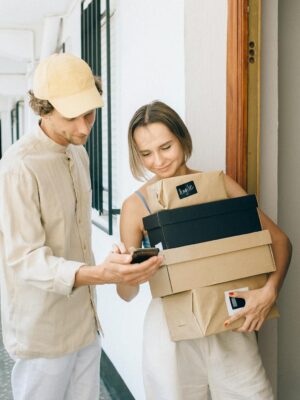 A man and woman engaged in a home delivery package exchange, smiling.